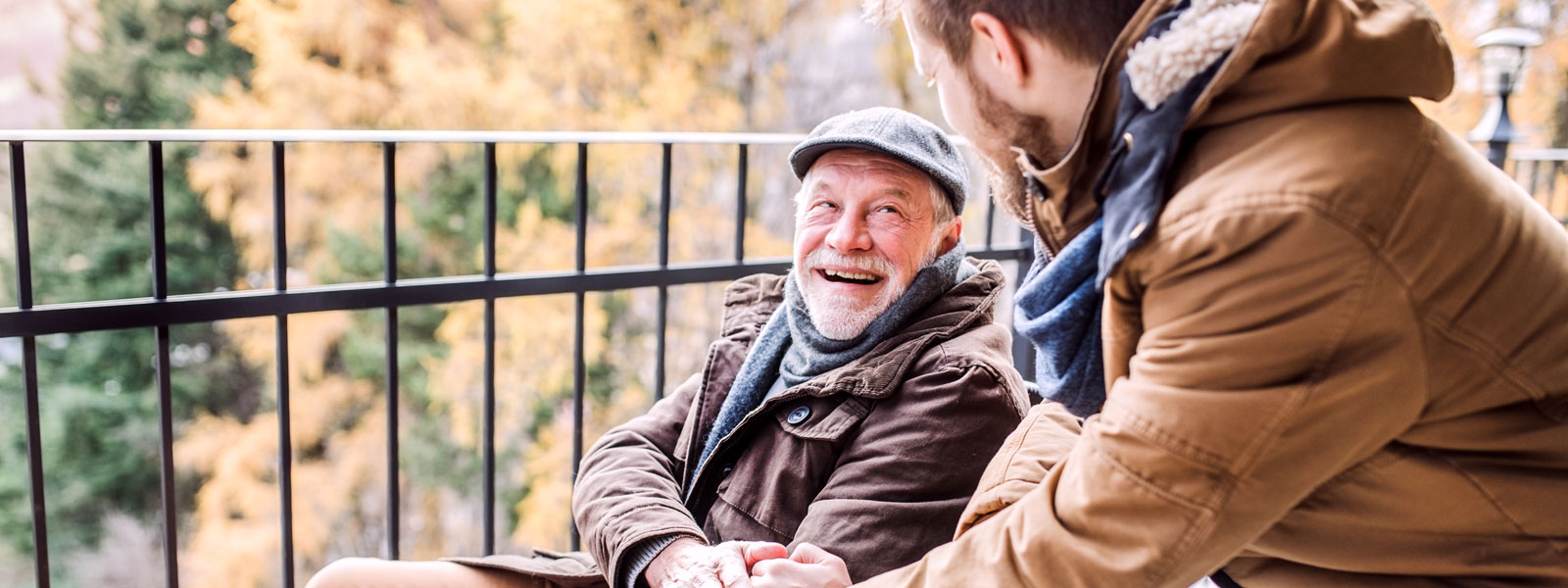 older man smiling at son outside